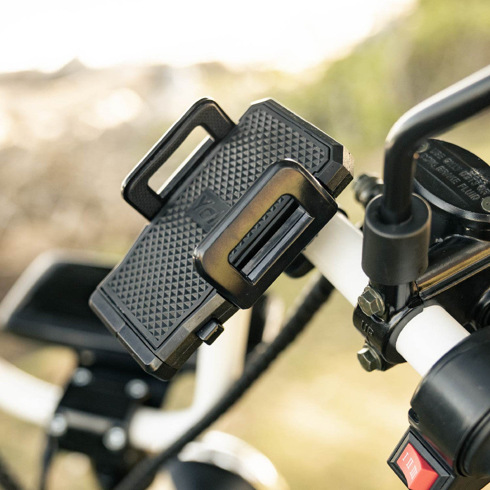 Close-up of a black cruzer phone mount on handlebars with a blurred natural background